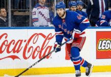 NY Rangers defenseman Vladislav Gavrikov (#44), currently the subject of intense trade rumors amid reports he is unhappy with the team's rebuild, skates with the puck past Coca-Cola and LEGO advertisements on the boards.
