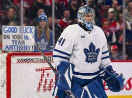Toronto Maple Leafs goaltender Anthony Stolarz (#41) stands in his crease during a game. Behind the protective glass, a female fan in a Leafs jersey and beanie holds a handwritten sign that reads, "GOOD LUCK ON YOUR NEW TEAM ANTHONY!".