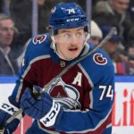 Colorado Avalanche forward Bobby McMann (74) looking up on the ice, wearing the team's maroon home jersey and a blue helmet during a game.