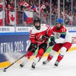 Team Canada women's hockey player skating with the puck against Team Czech Republic defender during 2026 Winter Olympics.