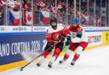 Team Canada women's hockey player skating with the puck against Team Czech Republic defender during 2026 Winter Olympics.