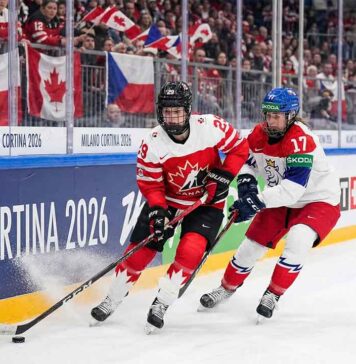 Team Canada women's hockey player skating with the puck against Team Czech Republic defender during 2026 Winter Olympics.