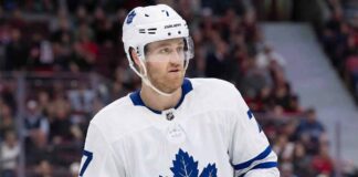 A photorealistic rendering of defenseman Dougie Hamilton standing on an ice hockey rink, wearing a white Toronto Maple Leafs away jersey with the blue Maple Leaf crest, blue gloves, and a white helmet bearing his number 7 and team decals.