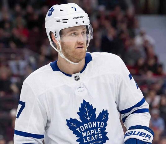 A photorealistic rendering of defenseman Dougie Hamilton standing on an ice hockey rink, wearing a white Toronto Maple Leafs away jersey with the blue Maple Leaf crest, blue gloves, and a white helmet bearing his number 7 and team decals.