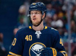 NHL player Elias Pettersson is pictured on an ice hockey rink wearing a dark blue Buffalo Sabres home jersey featuring the primary buffalo logo and number 40, along with a matching helmet and gloves, looking upwards to his left.