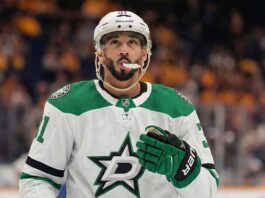 Vancouver Canucks forward Evander Kane pictured in a concept white Dallas Stars road uniform, wearing green and black Stars gloves and a white Bauer helmet with his mouthguard visible, looking upwards while standing on the ice.