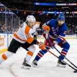 Will the Philadelphia Flyers Upset the New York Rangers Tonight? An action photograph from an NHL game showing Philadelphia Flyers forward Travis Konecny (left, in white #11 jersey) and New York Rangers center Mika Zibanejad (right, in blue #93 jersey) intensely battling for control of a loose puck on the ice.