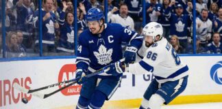 Toronto Maple Leafs captain Auston Matthews battles for possession of the puck against Tampa Bay Lightning forward Nikita Kucherov along the boards during an NHL game at Amalie Arena.