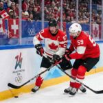 Team Canada captain Sidney Crosby (87) and Team Switzerland captain Roman Josi (59) battle fiercely for possession of the puck along the boards during a preliminary round men's hockey game at the 2026 Milano Cortina Winter Olympics.