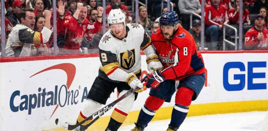 Will the Banged-Up Vegas Golden Knights Survive the Washington Capitals? Vegas Golden Knights forward Jack Eichel (9), wearing a white away jersey, and Washington Capitals captain Alex Ovechkin (8), wearing a red home jersey, engage in a physical battle with their sticks for the puck along the rink boards in front of cheering fans at Capital One Arena.