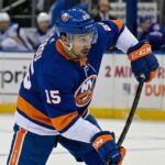 St. Louis Blues forward Jordan Kyrou is pictured in a New York Islanders blue home uniform, number 15, taking a shot during a hockey game.