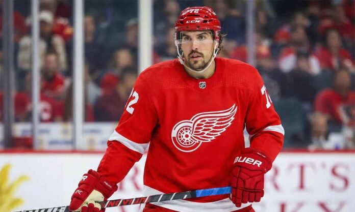 Detroit Red Wings defenseman Justin Faulk, wearing the red home jersey with number 72 and a red helmet, stands on the ice holding his stick during a game.