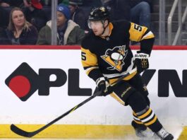 Pittsburgh Penguins defenseman Luke Schenn wearing the team's black home uniform and helmet, skating on the ice and looking intently forward during a game.