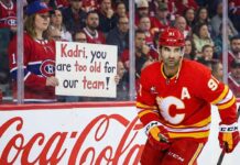 Calgary Flames center Nazem Kadri skates past a female Montreal Canadiens fan holding a handwritten sign that reads "Kadri, you are too old for our team!" during an NHL game.