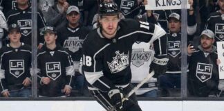 A visualization of hockey player Robert Thomas wearing a black No. 18 Los Angeles Kings jersey, skating intently on the ice while fans in casual clothing watch from behind the glass.