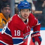 Montreal Canadiens center Robert Thomas (18), wearing the team's red home jersey and blue helmet, skates on the ice during a game, looking towards the camera.