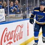 St. Louis Blues center Robert Thomas smiles as he skates past a female fan behind the glass holding a handmade sign that reads "Good luck in Utah Robert!" amidst heavy trade rumors involving the Utah Mammoth.