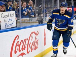 St. Louis Blues center Robert Thomas smiles as he skates past a female fan behind the glass holding a handmade sign that reads "Good luck in Utah Robert!" amidst heavy trade rumors involving the Utah Mammoth.