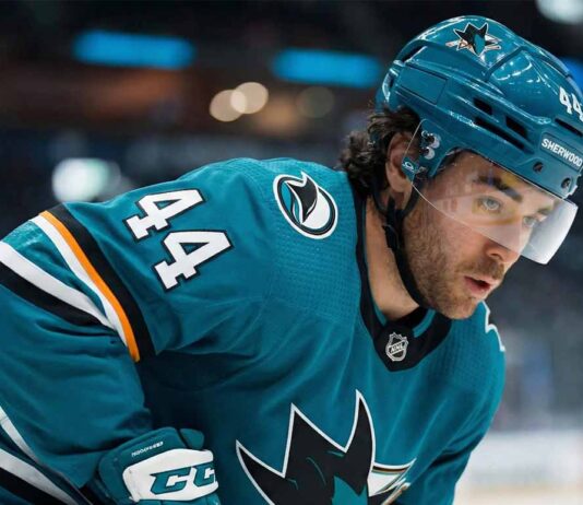The San Jose Sharks Just Got Kiefer Sherwood. Why Move Him Now? Kiefer Sherwood, wearing a teal San Jose Sharks uniform, looks over his shoulder on the ice amidst growing NHL trade deadline rumors regarding his future with the struggling team.