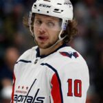 Artemi Panarin in a white Washington Capitals jersey and helmet, number 10, looking towards the right with his tongue out.