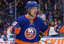 Vancouver Canucks center Elias Pettersson, wearing the 'Flying Skate' retro jersey, celebrating a goal, amidst New York Islanders trade speculation.