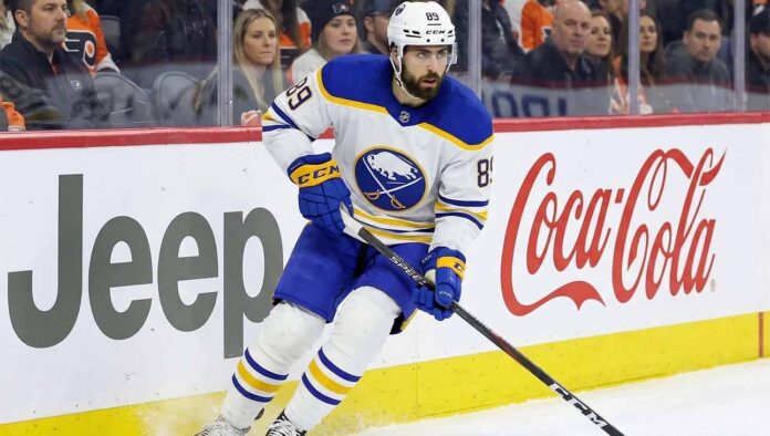 Buffalo Sabres winger Alex Tuch (number 89) skating hard along the rink boards featuring Jeep and Coca-Cola advertising during a home game. This image relates to current discussions about Tuch's contract extension and potential free agency.