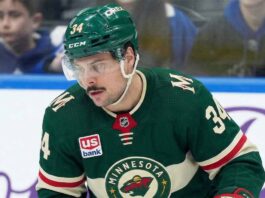 A close-up of Toronto Maple Leafs captain Auston Matthews (#34) in a Minnesota Wild jersey on the ice, appearing focused. Matthews is central to recent blockbuster NHL trade rumors linking him to the Wild.