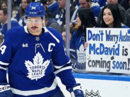 The Unthinkable Reality: Is Auston Matthews Done With the Toronto Maple Leafs? Toronto Maple Leafs captain Auston Matthews skates by the boards as a fan holds a controversial sign reading 'Don't Worry Auston, McDavid is coming soon!' highlighting fan frustration and future roster rumors.