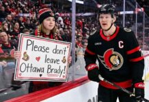 Ottawa Senators captain Brady Tkachuk skating past an emotional fan holding a handwritten sign that reads, "Please don't leave Ottawa Brady!" amid NHL trade rumors.