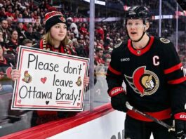 Ottawa Senators captain Brady Tkachuk skating past an emotional fan holding a handwritten sign that reads, "Please don't leave Ottawa Brady!" amid NHL trade rumors.