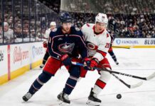 Sebastian Aho of the Carolina Hurricanes and Adam Fantilli of the Columbus Blue Jackets battle for the puck on the ice during their NHL game on Tuesday, March 31, 2026.