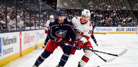 Sebastian Aho of the Carolina Hurricanes and Adam Fantilli of the Columbus Blue Jackets battle for the puck on the ice during their NHL game on Tuesday, March 31, 2026.