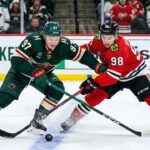 Kirill Kaprizov and Connor Bedard battling for a loose puck during a Chicago Blackhawks vs. Minnesota Wild game.