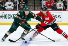 Kirill Kaprizov and Connor Bedard battling for a loose puck during a Chicago Blackhawks vs. Minnesota Wild game.