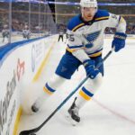 St. Louis Blues defenseman Colton Parayko in a white away jersey skates with the puck along the boards at KeyBank Center, home of the Buffalo Sabres.
