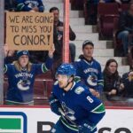 Conor Garland skates past a Vancouver Canucks fan holding a farewell sign amidst intensifying NHL trade rumors linking him to the Boston Bruins and New York Islanders.