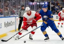 Dylan Larkin of the Detroit Red Wings battles Rasmus Dahlin of the Buffalo Sabres for the puck on the ice at KeyBank Center during an NHL Atlantic Division game.