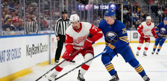 Dylan Larkin of the Detroit Red Wings battles Rasmus Dahlin of the Buffalo Sabres for the puck on the ice at KeyBank Center during an NHL Atlantic Division game.