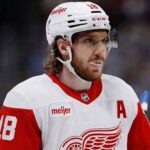 Concept image depicting NHL star Robert Thomas wearing a white Detroit Red Wings away uniform and helmet with visor, visualizing the potential trade acquisition from the St. Louis Blues that Steve Yzerman passed on before the 2026 trade deadline.