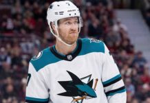 Pensive Dougie Hamilton wearing a white San Jose Sharks away uniform with teal accents, illustrating potential NHL trade rumors.