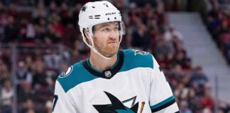 Pensive Dougie Hamilton wearing a white San Jose Sharks away uniform with teal accents, illustrating potential NHL trade rumors.
