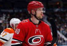 Elias Pettersson of the Vancouver Canucks, wearing the blue orca jersey, looks focused on the ice during an NHL game, fueling trade rumors linking him to the Carolina Hurricanes.