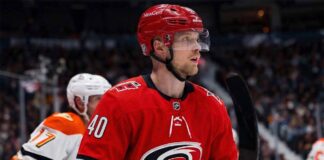 Elias Pettersson of the Vancouver Canucks, wearing the blue orca jersey, looks focused on the ice during an NHL game, fueling trade rumors linking him to the Carolina Hurricanes.