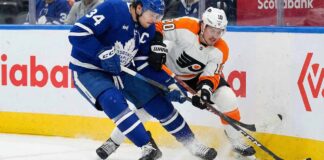 Auston Matthews of the Toronto Maple Leafs and Travis Konecny of the Philadelphia Flyers battle for the puck along the boards during an NHL game.