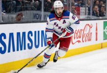 New York Rangers forward Mika Zibanejad (93) skating with the puck along the boards during an NHL game.