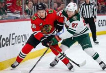 Minnesota Wild star Kirill Kaprizov (#97) and Chicago Blackhawks phenom Connor Bedard (#98) face off, battling fiercely for a loose puck during a recent hockey game.