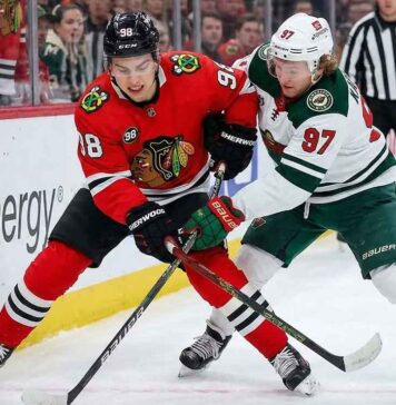 Minnesota Wild star Kirill Kaprizov (#97) and Chicago Blackhawks phenom Connor Bedard (#98) face off, battling fiercely for a loose puck during a recent hockey game.