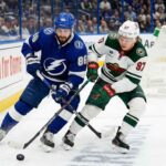 Nikita Kucherov of the Tampa Bay Lightning battles for the puck against Kirill Kaprizov of the Minnesota Wild during their 2025-26 NHL regular season matchup on Tuesday, March 24, 2026.