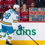 St. Louis Blues player Robert Thomas skates as a Montreal Canadiens fan holds a homemade sign saying "COME TO MONTREAL THIS SUMMER ROBERT!", fueled by persistent Canadiens NHL trade rumors.