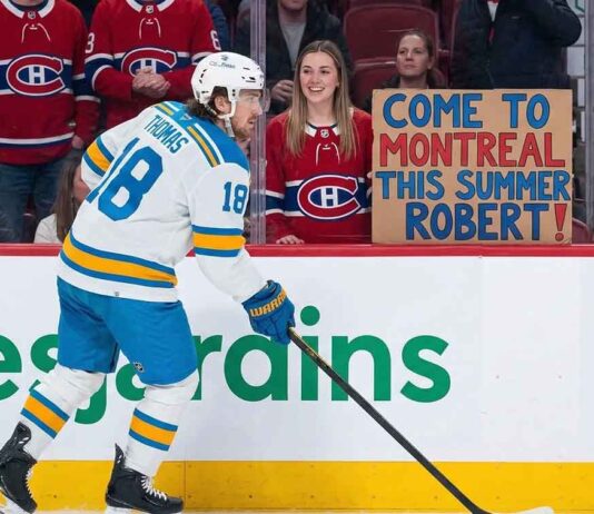 St. Louis Blues player Robert Thomas skates as a Montreal Canadiens fan holds a homemade sign saying "COME TO MONTREAL THIS SUMMER ROBERT!", fueled by persistent Canadiens NHL trade rumors.